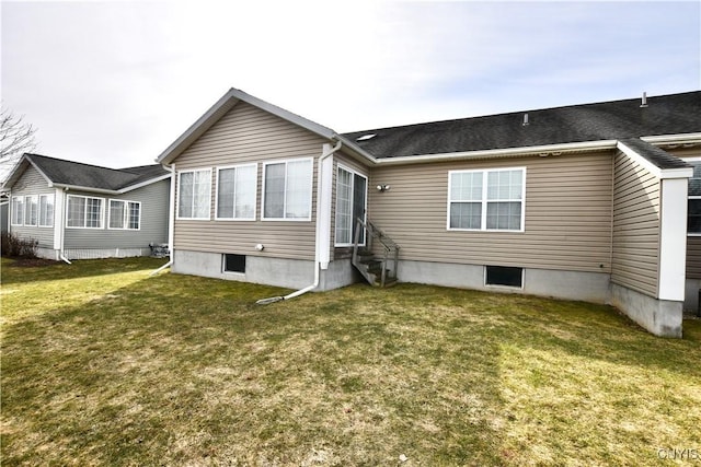 rear view of property featuring a lawn and entry steps