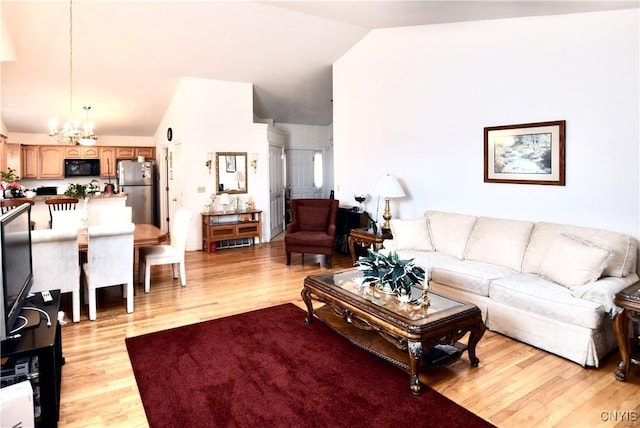 living area featuring vaulted ceiling, light wood finished floors, and a chandelier