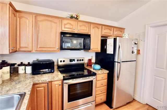 kitchen featuring light wood-style flooring, light brown cabinetry, a sink, light stone counters, and appliances with stainless steel finishes