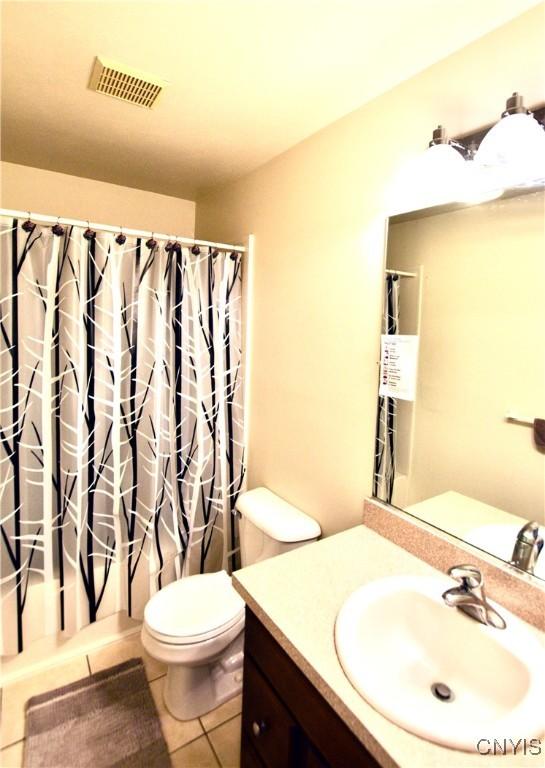 bathroom with visible vents, toilet, a shower with shower curtain, tile patterned floors, and vanity