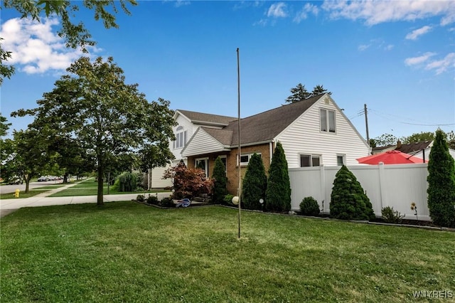 view of home's exterior featuring a yard, fence, and brick siding