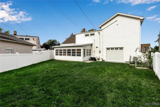 back of property featuring a sunroom, a lawn, a garage, a fenced backyard, and driveway