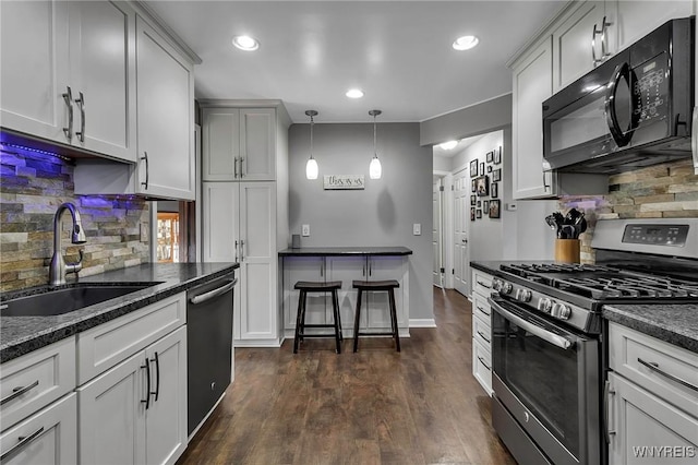 kitchen featuring stainless steel gas range oven, black microwave, dishwasher, dark wood-style floors, and a sink