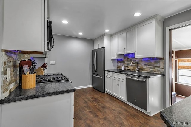 kitchen with dark wood-type flooring, a sink, dark countertops, appliances with stainless steel finishes, and white cabinets