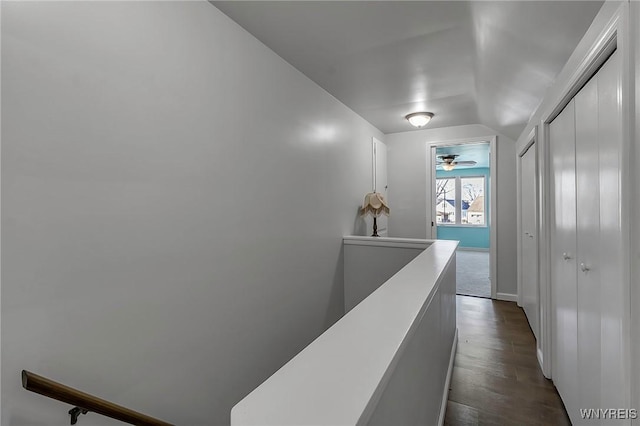 hall featuring an upstairs landing, dark wood-type flooring, and vaulted ceiling