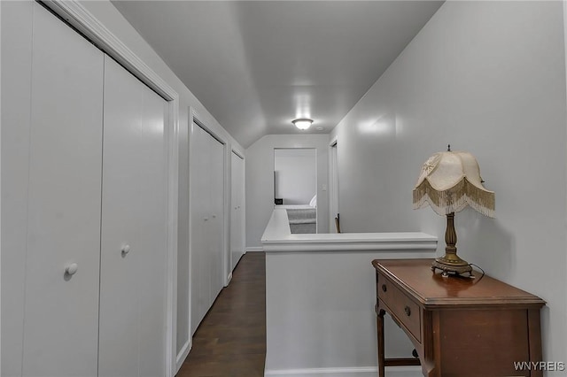 corridor with lofted ceiling and dark wood-style floors