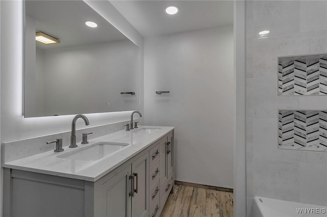 bathroom featuring double vanity, recessed lighting, wood finished floors, and a sink