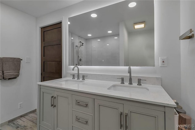 full bath with double vanity, recessed lighting, a tile shower, and a sink