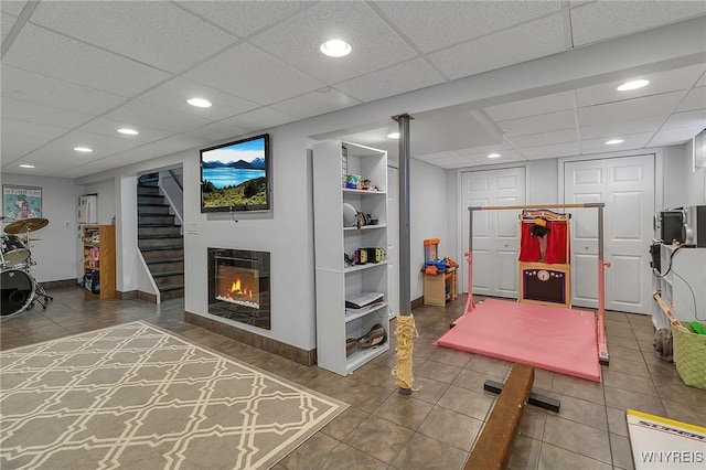 rec room with built in shelves, baseboards, recessed lighting, tile patterned flooring, and a glass covered fireplace