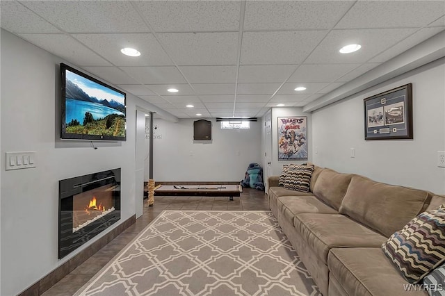 living room featuring recessed lighting, a drop ceiling, wood finished floors, and a glass covered fireplace