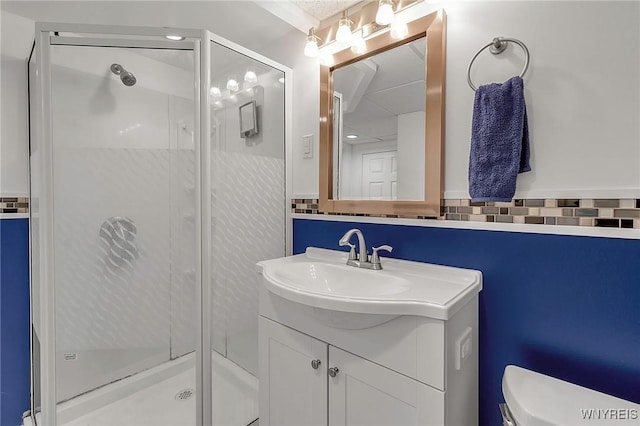 bathroom with backsplash, a stall shower, toilet, and vanity