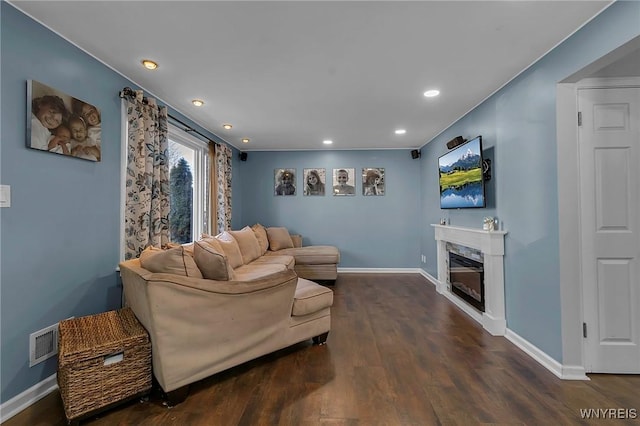 living area with visible vents, baseboards, dark wood-type flooring, and a premium fireplace