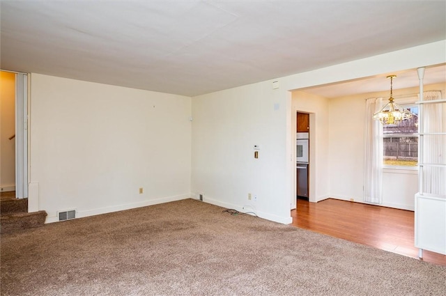 spare room featuring visible vents, carpet, an inviting chandelier, and stairs