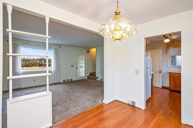 unfurnished dining area with stairs, visible vents, wood finished floors, and carpet flooring