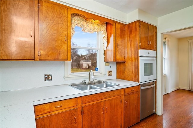 kitchen featuring brown cabinets, light countertops, dark wood-type flooring, and a sink