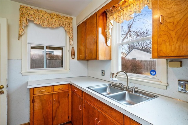 kitchen with brown cabinetry, light countertops, and a sink