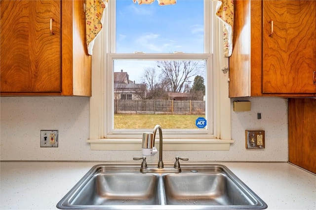 kitchen featuring light countertops, brown cabinets, and a sink