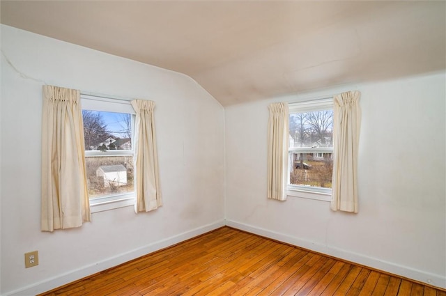 spare room with baseboards, lofted ceiling, and hardwood / wood-style floors