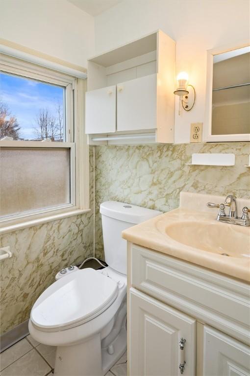 half bathroom with tile patterned floors, toilet, and vanity