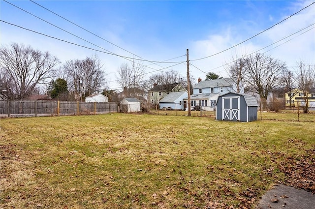 view of yard with an outdoor structure, a fenced backyard, and a shed