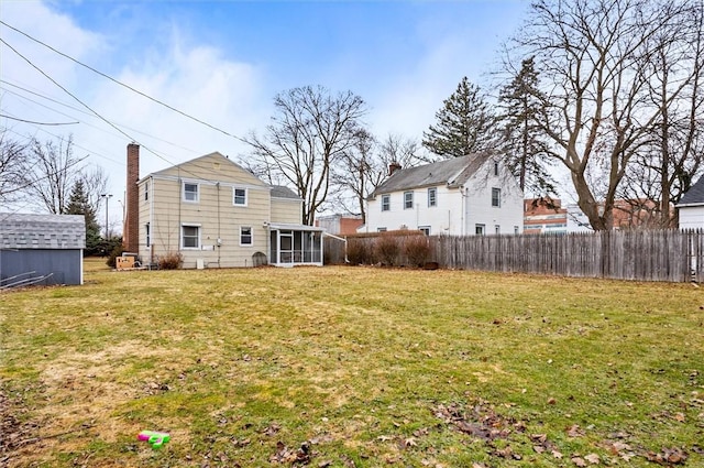 view of yard featuring a shed, fence, an outdoor structure, and a sunroom