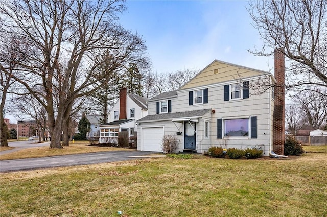 traditional-style home with fence, driveway, an attached garage, a chimney, and a front lawn