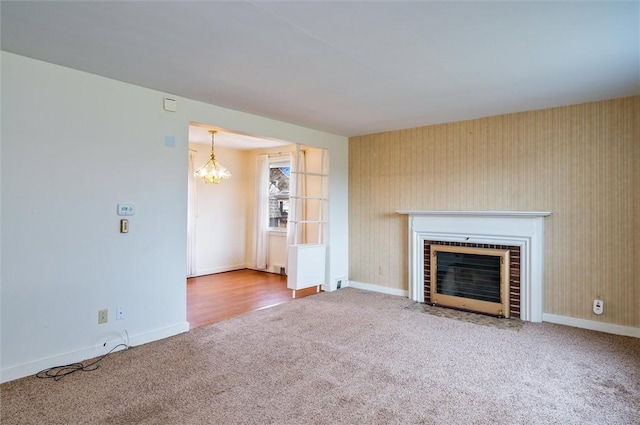 unfurnished living room with a notable chandelier, a fireplace with flush hearth, baseboards, and carpet