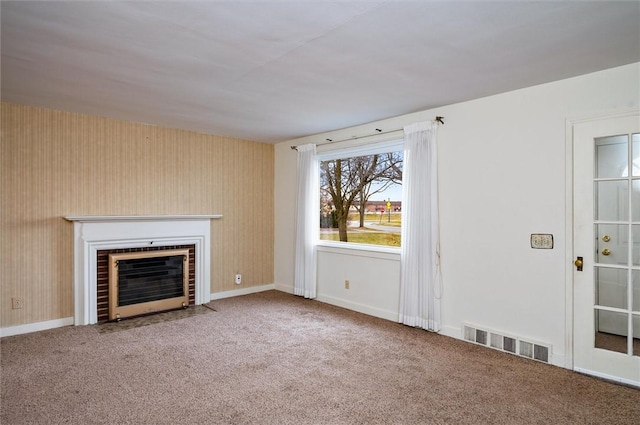 unfurnished living room featuring visible vents, a fireplace, baseboards, and carpet floors