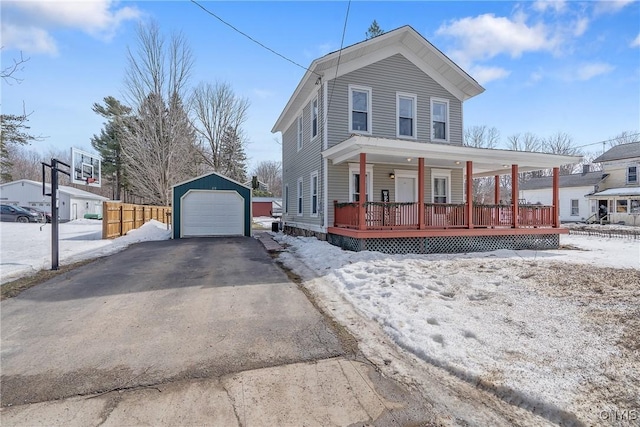 view of front of house featuring fence, aphalt driveway, a porch, an outdoor structure, and a garage