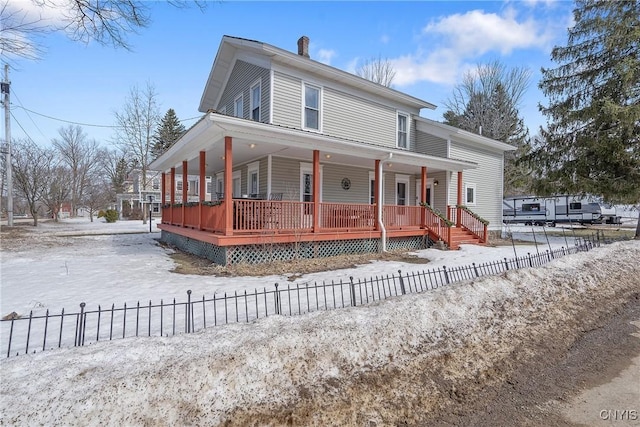 farmhouse featuring a fenced front yard, covered porch, and a chimney