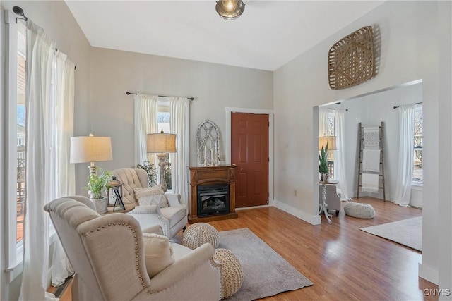 living room with a glass covered fireplace, baseboards, and wood finished floors