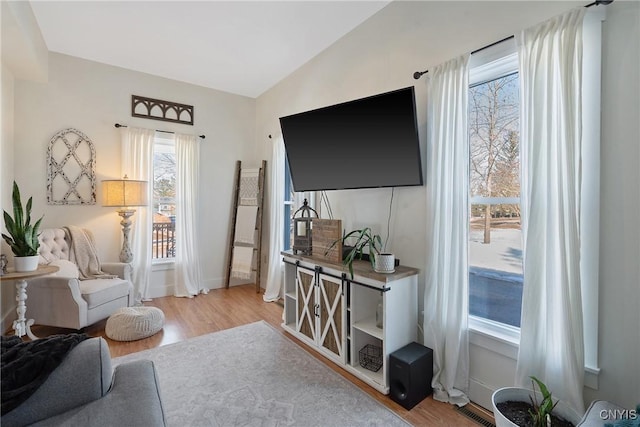 living room featuring visible vents, baseboards, wood finished floors, and vaulted ceiling