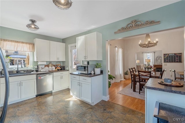 kitchen with a sink, dark countertops, appliances with stainless steel finishes, and white cabinets