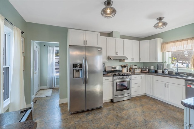 kitchen with under cabinet range hood, white cabinets, appliances with stainless steel finishes, and a sink