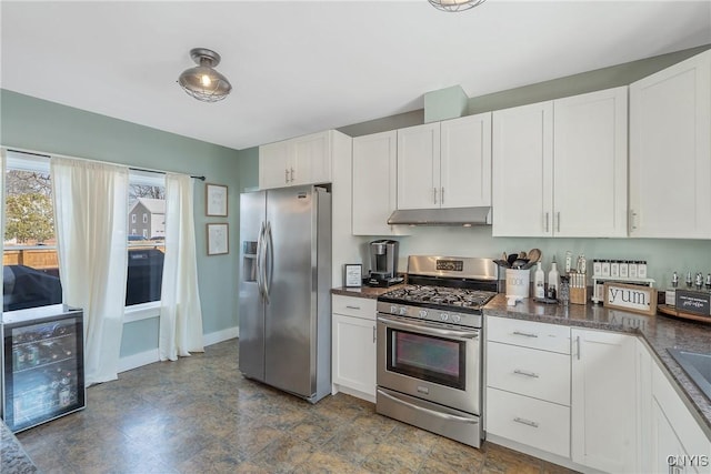 kitchen featuring under cabinet range hood, dark countertops, appliances with stainless steel finishes, white cabinets, and baseboards