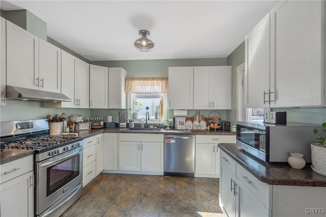 kitchen with under cabinet range hood, a sink, dark countertops, stainless steel appliances, and white cabinets