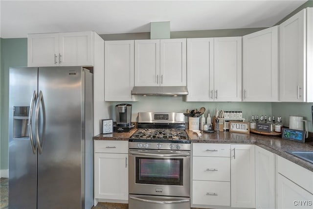 kitchen featuring under cabinet range hood, white cabinets, appliances with stainless steel finishes, and dark stone counters