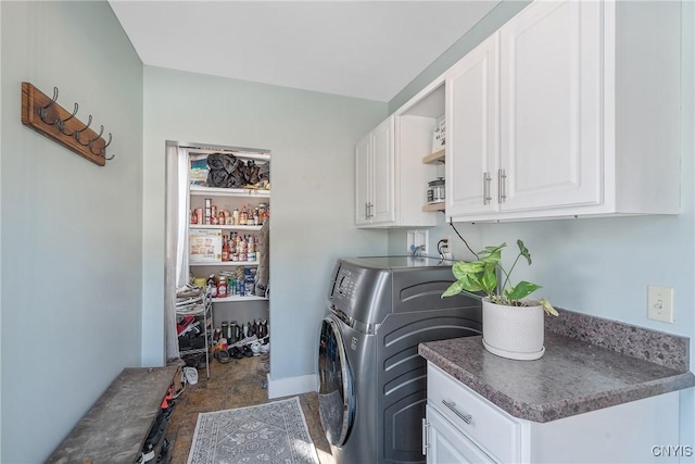 clothes washing area featuring cabinet space and baseboards