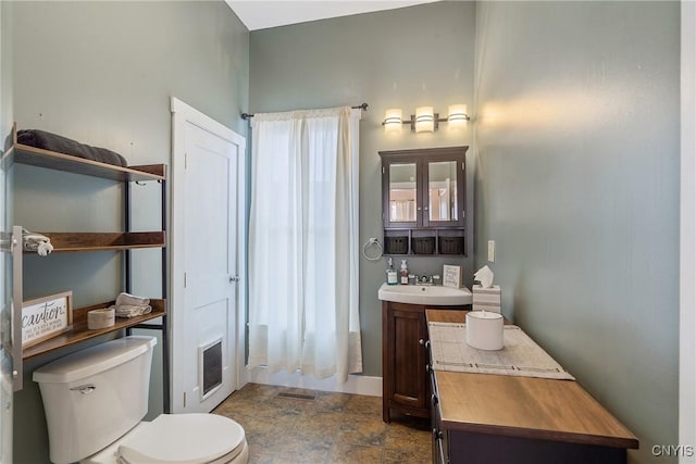 bathroom featuring visible vents, baseboards, toilet, stone finish floor, and vanity