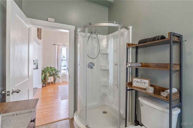 full bath with toilet, wood finished floors, and a shower stall