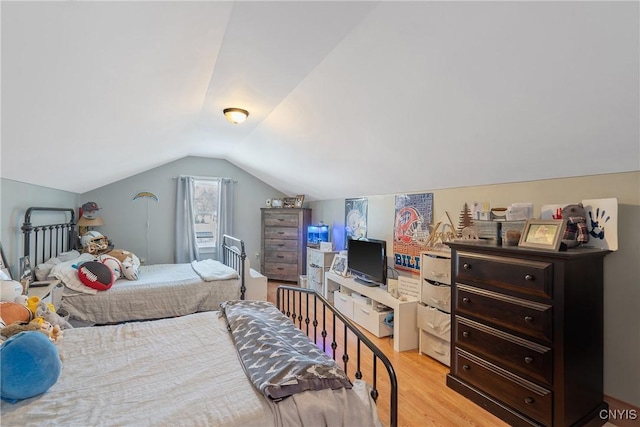 bedroom with light wood-style floors and vaulted ceiling