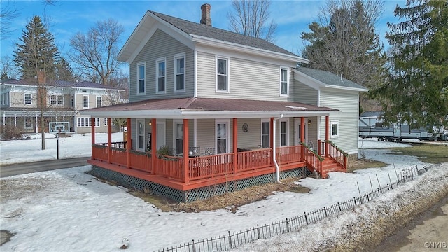 farmhouse inspired home featuring a porch, a chimney, and fence