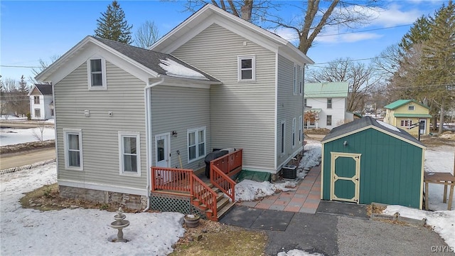 exterior space with cooling unit, a storage shed, an outdoor structure, and roof with shingles