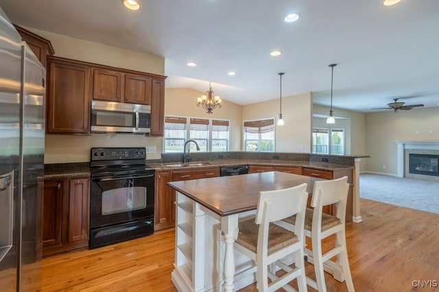 kitchen with black appliances, a sink, recessed lighting, a peninsula, and a tile fireplace