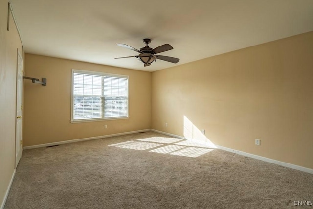 empty room with visible vents, carpet, baseboards, and ceiling fan