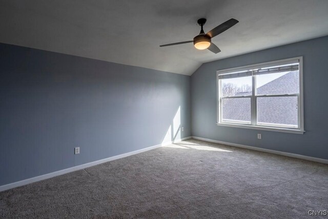 carpeted empty room featuring vaulted ceiling, a ceiling fan, and baseboards