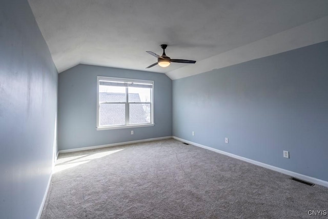 carpeted empty room featuring visible vents, a ceiling fan, baseboards, and vaulted ceiling