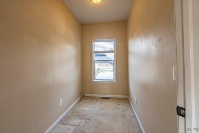 unfurnished room featuring baseboards and light carpet