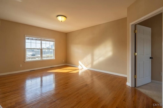 empty room with visible vents, baseboards, and wood finished floors