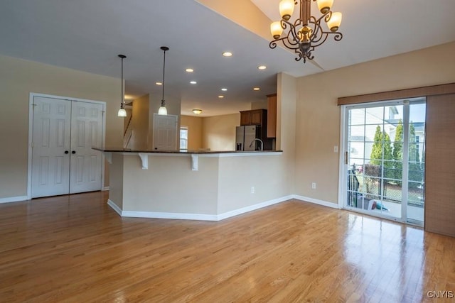 kitchen featuring recessed lighting, light wood-style flooring, baseboards, and stainless steel fridge with ice dispenser